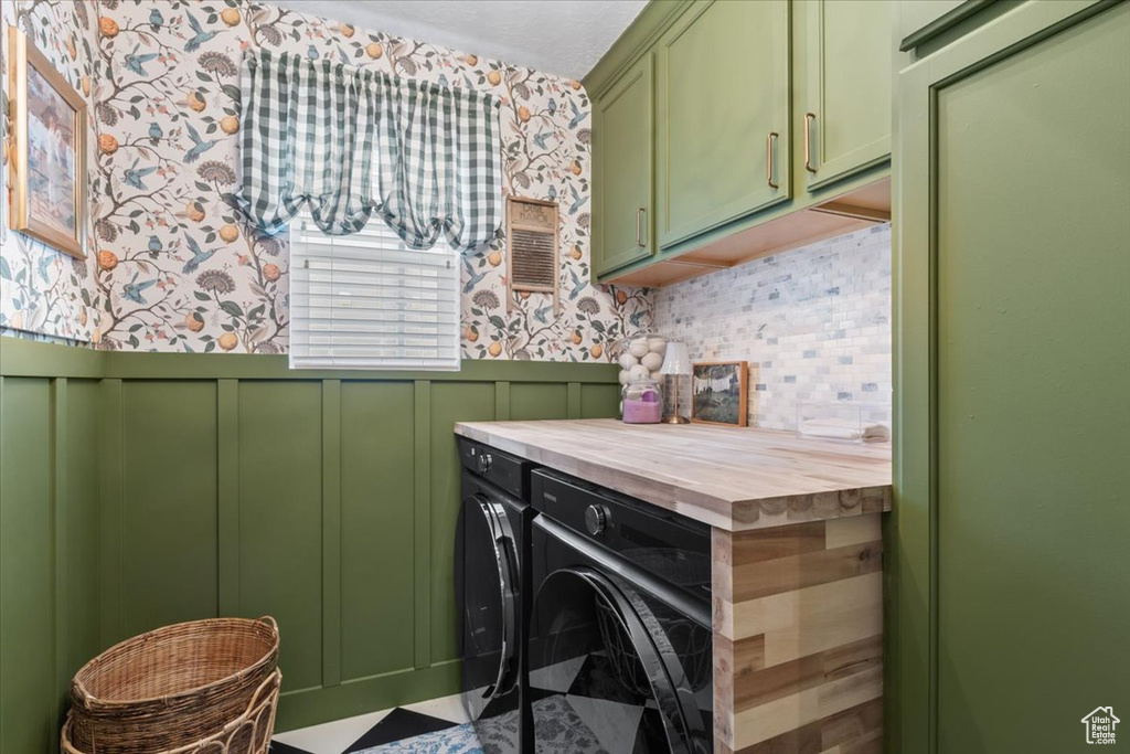 Laundry area featuring cabinet space, separate washer and dryer, wallpapered walls, a wainscoted wall, and a decorative wall