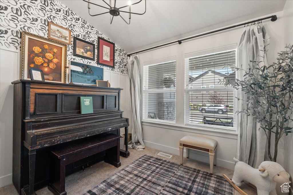 Sitting room with a chandelier, healthy amount of natural light, carpet, and vaulted ceiling