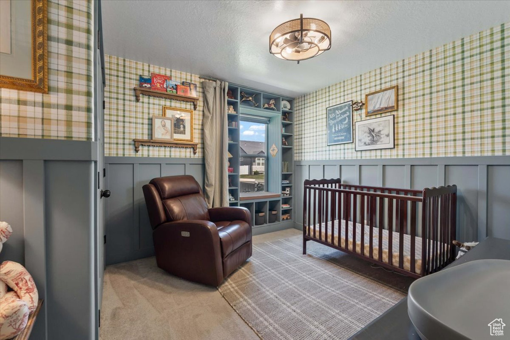 Bedroom featuring wallpapered walls, carpet flooring, wainscoting, a textured ceiling, and a decorative wall