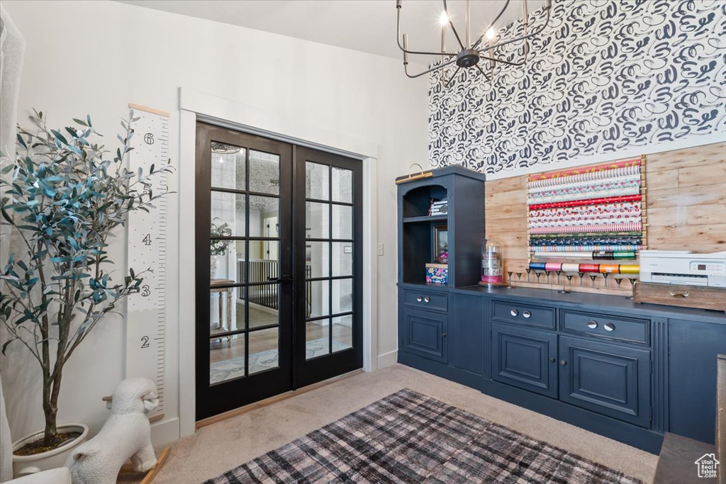 Carpeted foyer featuring french doors, a chandelier, healthy amount of natural light, and a towering ceiling