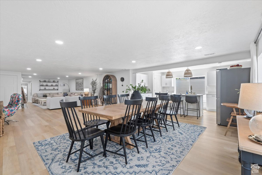 Dining room with recessed lighting, light wood-type flooring, and a textured ceiling