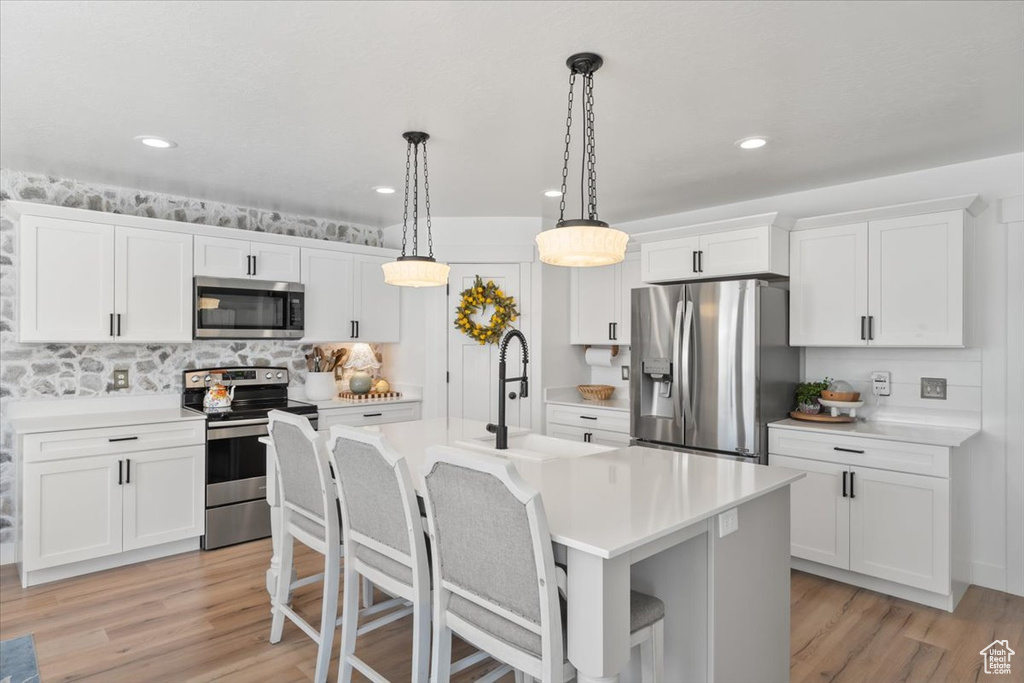 Kitchen featuring appliances with stainless steel finishes, light countertops, a breakfast bar, decorative light fixtures, and recessed lighting