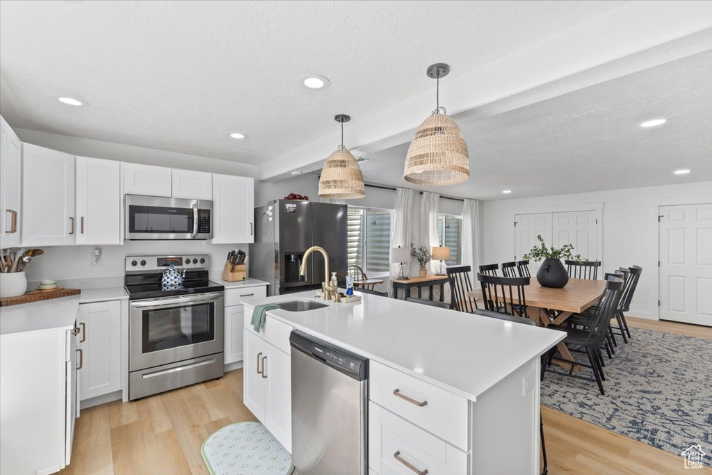 Kitchen featuring appliances with stainless steel finishes, light wood-style flooring, white cabinets, and recessed lighting