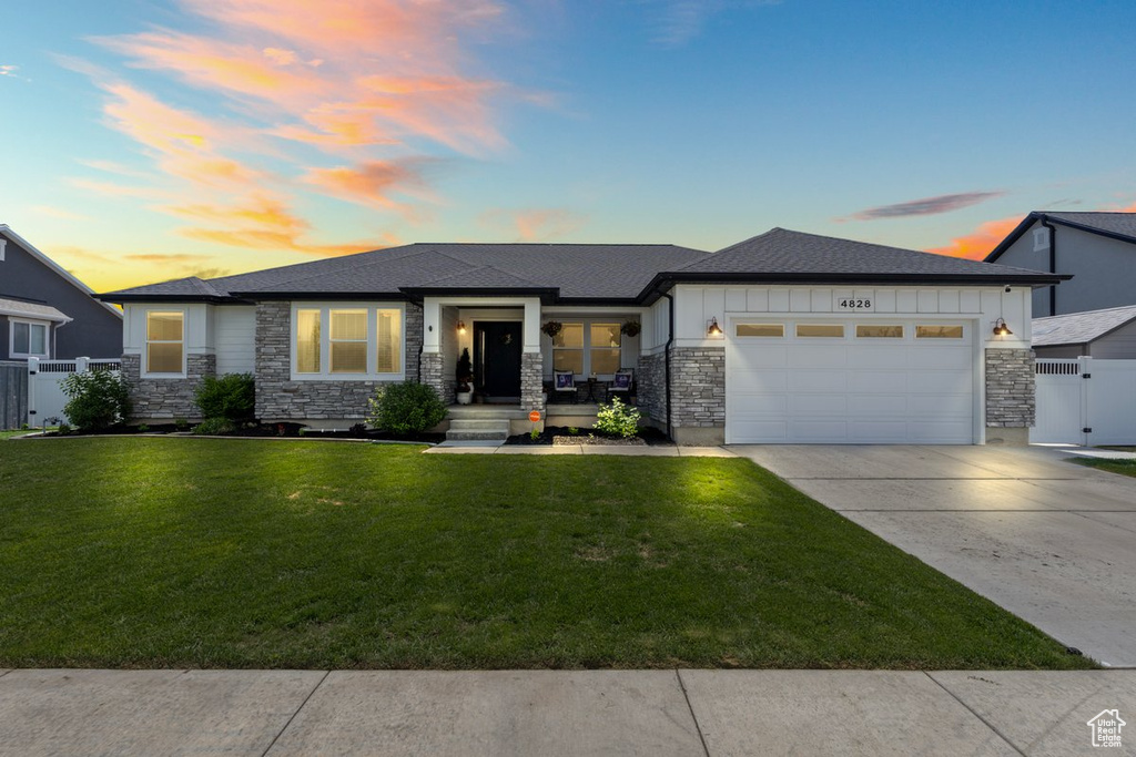 Prairie-style home with stone siding, a garage, concrete driveway, a gate, and a shingled roof