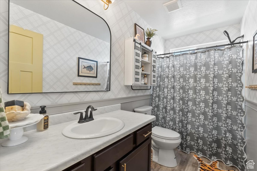 Bathroom with vanity, wood finished floors, a shower with shower curtain, and wallpapered walls