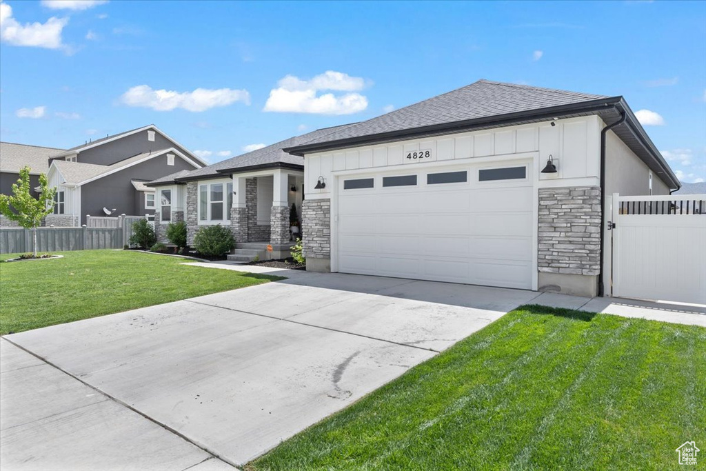 View of front of home featuring stone siding, board and batten siding, a garage, and concrete driveway