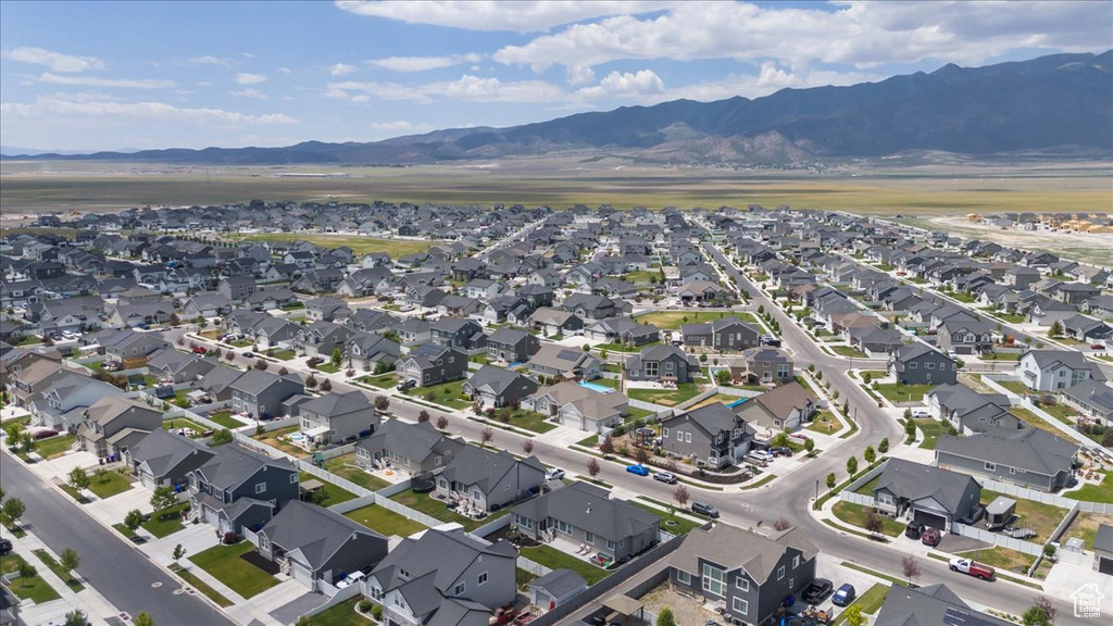 Aerial view of property and surrounding area featuring a mountainous background and nearby suburban area