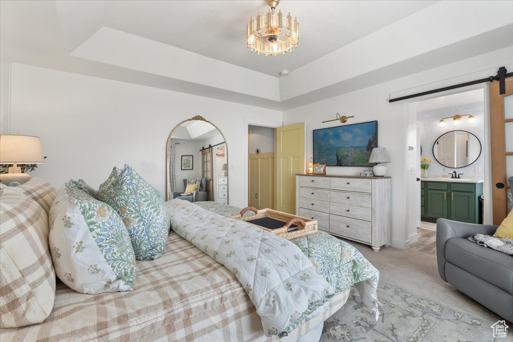 Bedroom with a barn door, light colored carpet, arched walkways, and connected bathroom