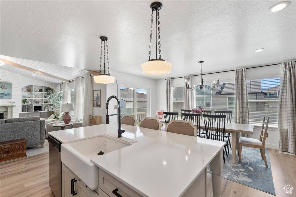 Kitchen with light wood-style flooring, decorative light fixtures, light countertops, recessed lighting, and stainless steel dishwasher