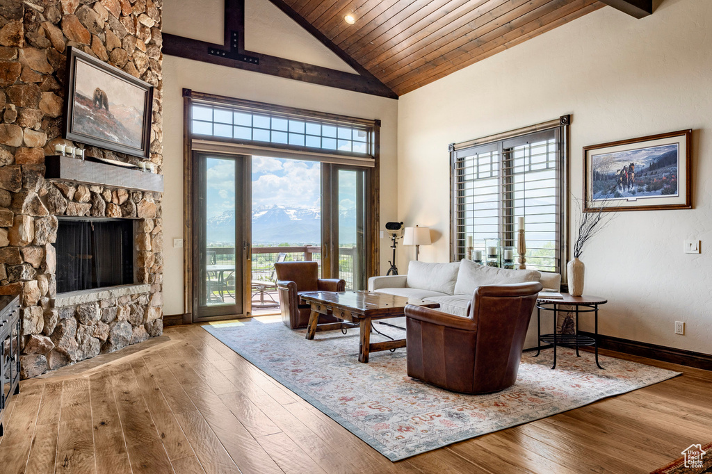 Living room featuring hardwood / wood-style flooring, wood ceiling, high vaulted ceiling, and a fireplace