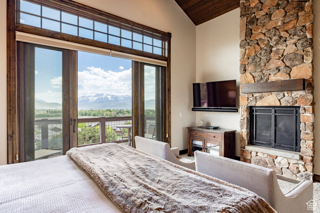 Bedroom featuring vaulted ceiling, access to exterior, wooden ceiling, and a stone fireplace