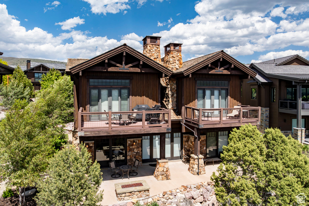 Rear view of property with a patio, stone siding, an outdoor fire pit, and a chimney