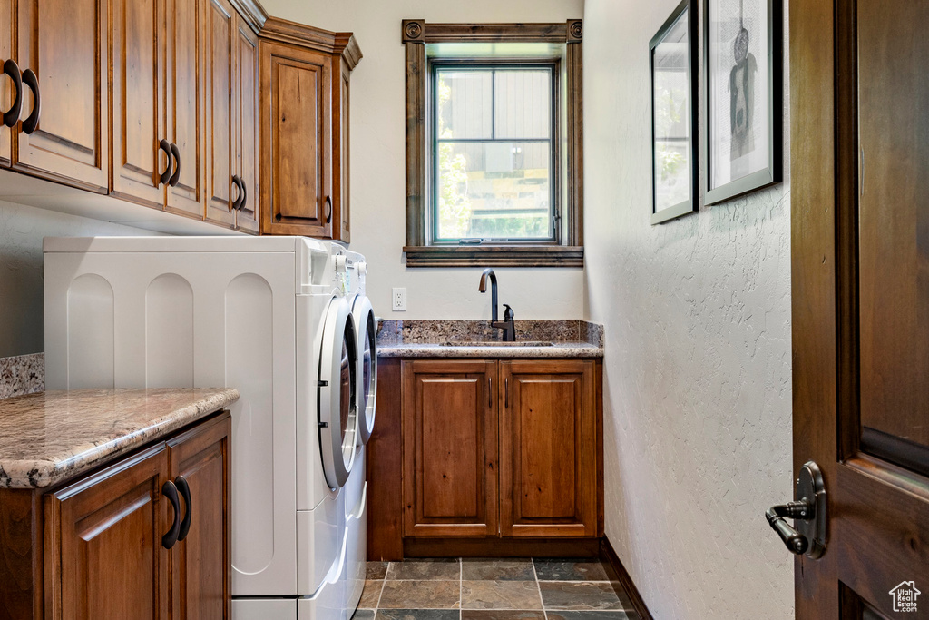 Laundry area with cabinet space and dark stone finish flooring