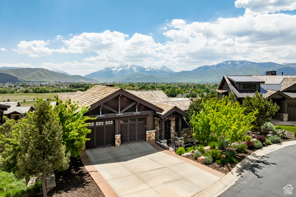 View of front of home with a mountain view, a garage, stone siding, and concrete driveway