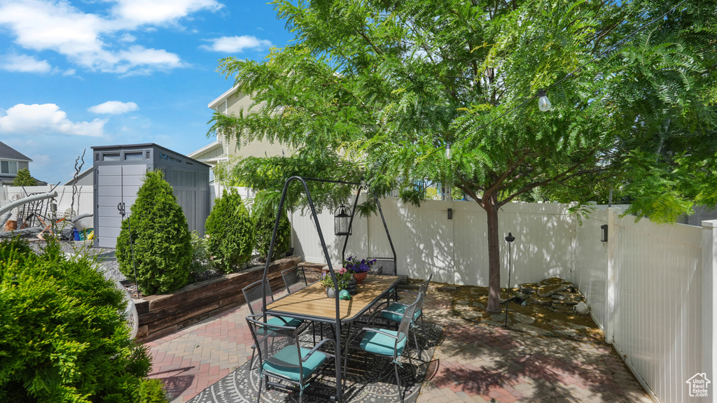 Fenced backyard with a shed, a patio, and outdoor dining area