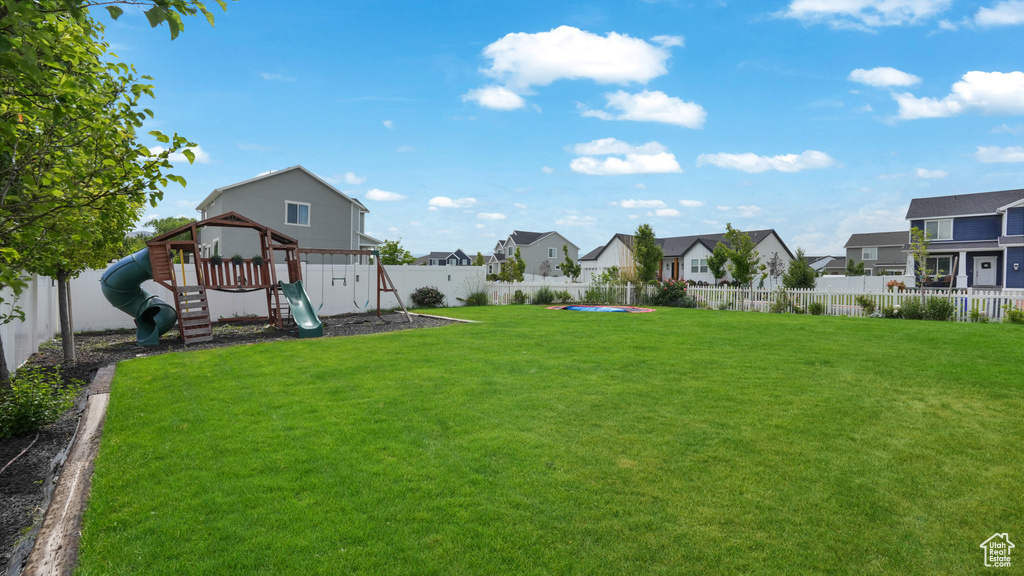 Fenced backyard with a residential view and a playground