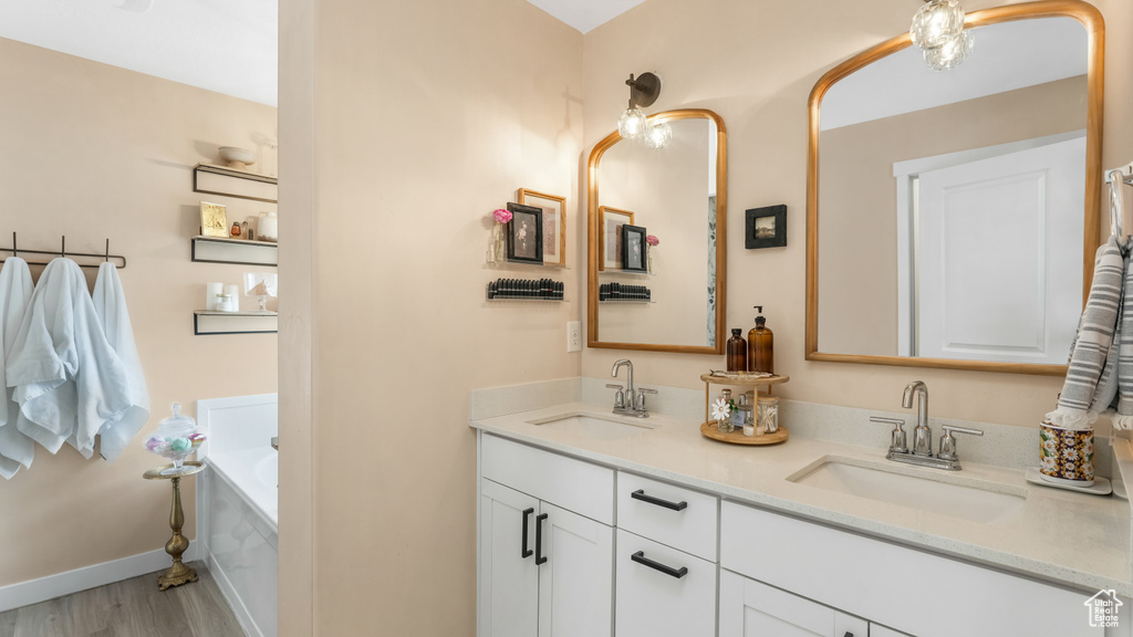 Bathroom with double vanity, wood finished floors, and a garden tub