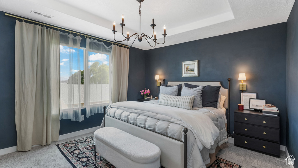 Bedroom featuring a chandelier, light carpet, and a tray ceiling
