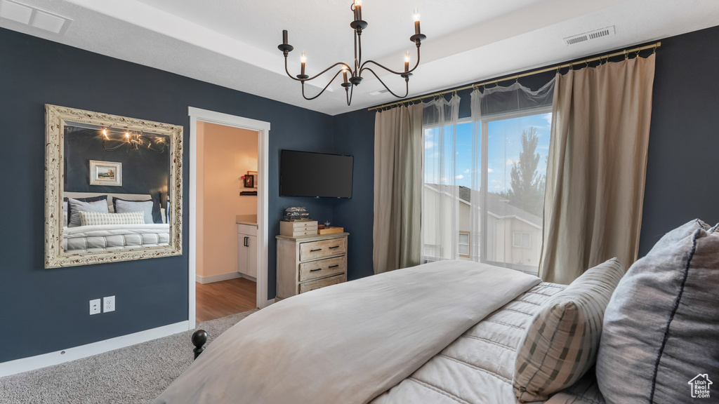 Carpeted bedroom with a chandelier and a raised ceiling