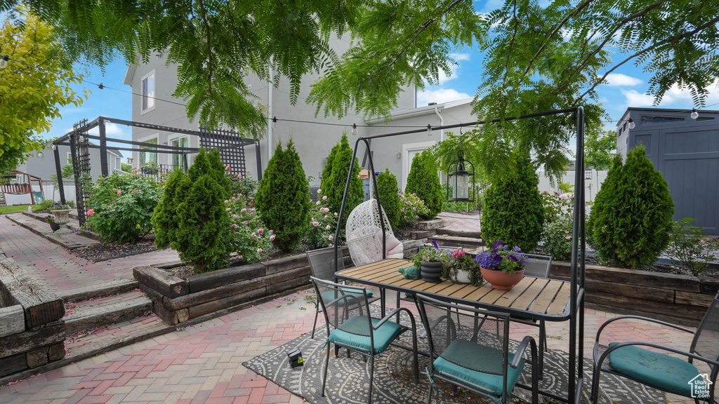 View of patio with outdoor dining space and a storage unit