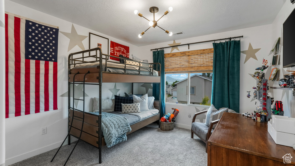 Carpeted bedroom with baseboards and a chandelier