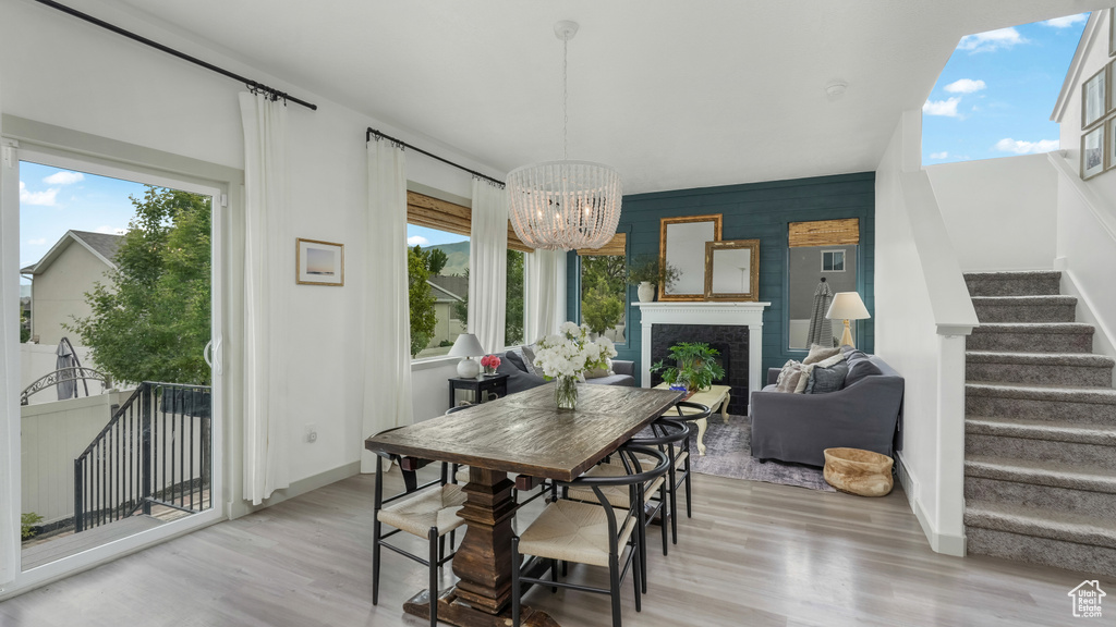 Dining area with stairs, wood finished floors, a chandelier, and plenty of natural light