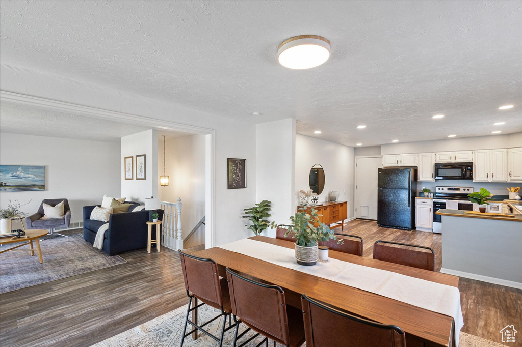 Dining area featuring dark wood-type flooring, recessed lighting, and a textured ceiling