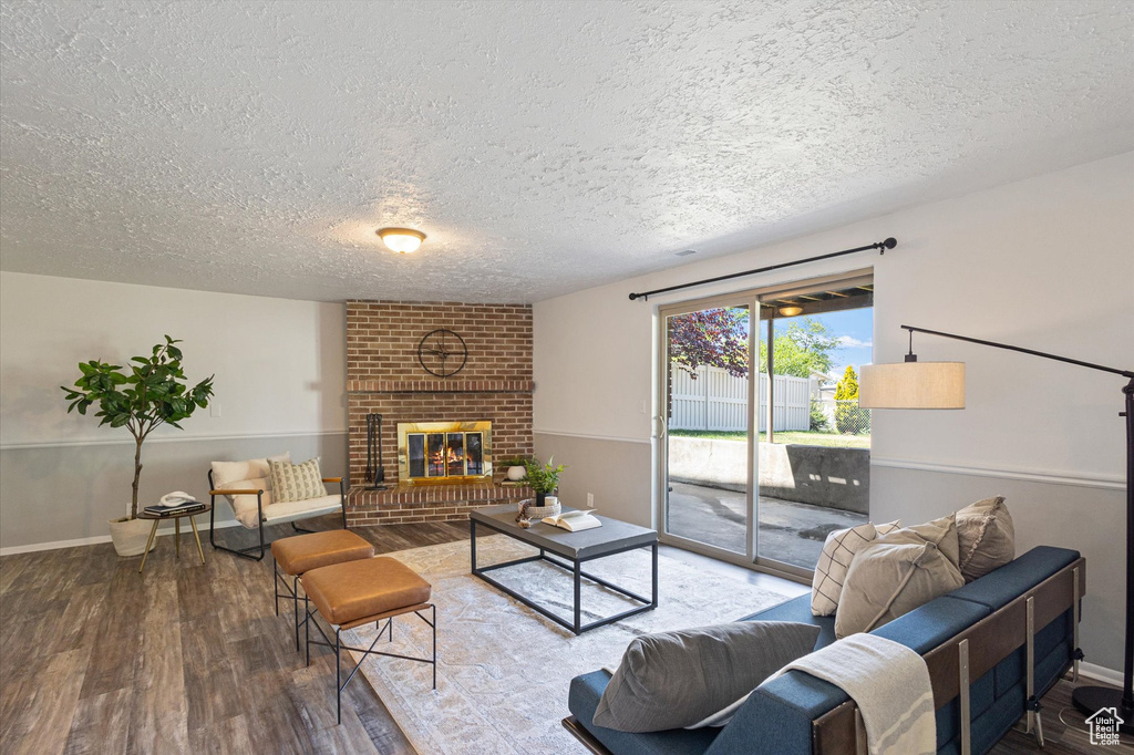 Living area with a textured ceiling, wood finished floors, a fireplace, and baseboards