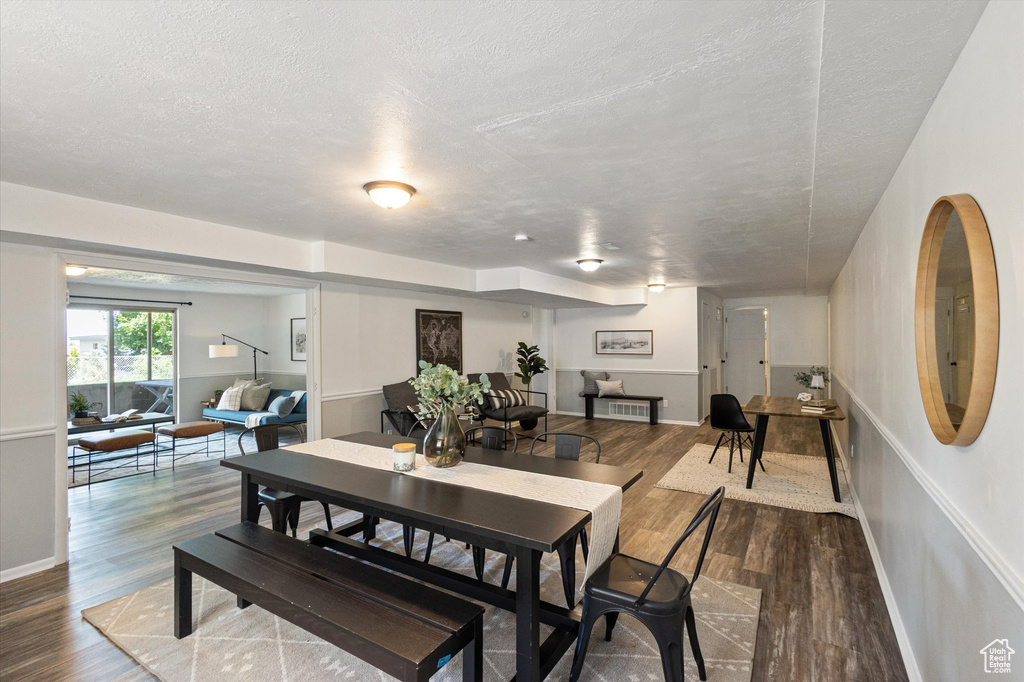 Dining room with a textured ceiling, wood finished floors, and baseboards