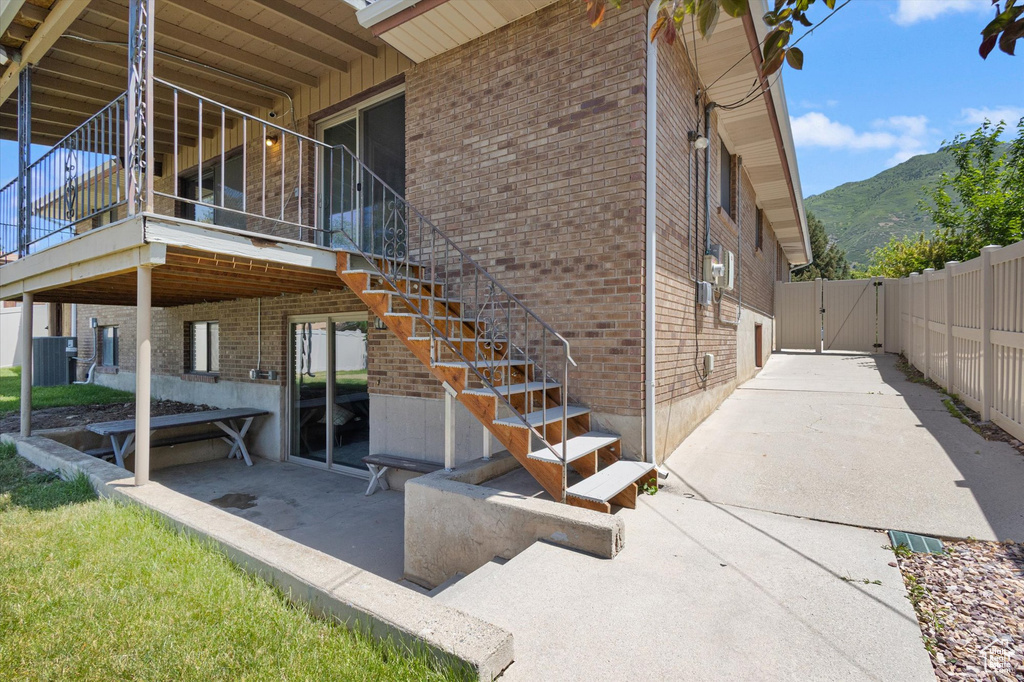 View of property exterior featuring a gate, brick siding, a mountain view, and a patio area
