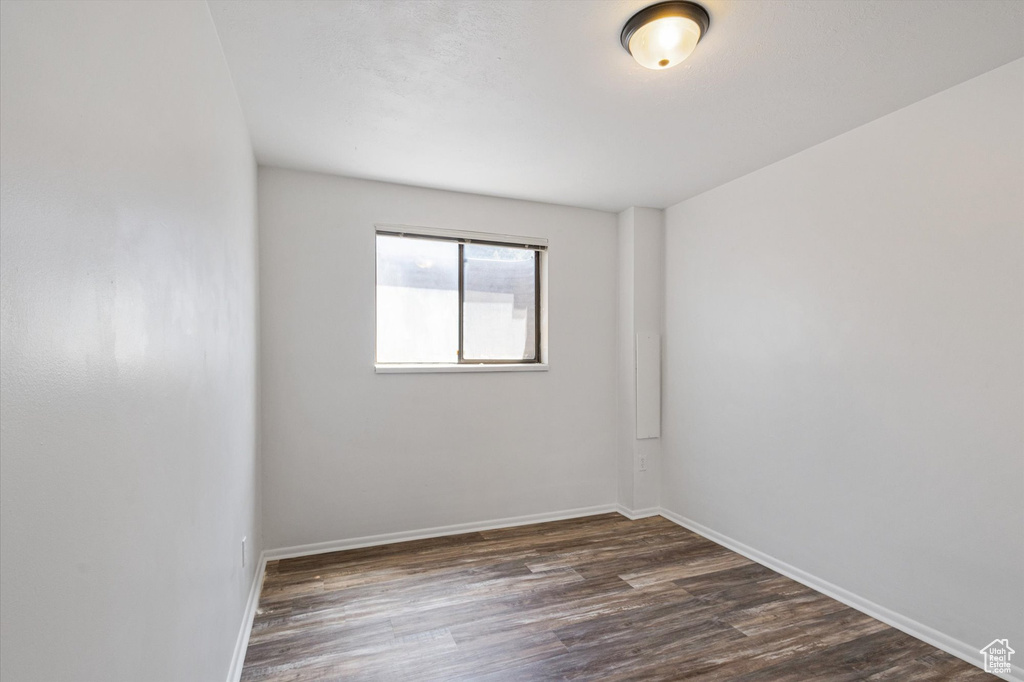 Empty room featuring dark wood-style flooring and baseboards