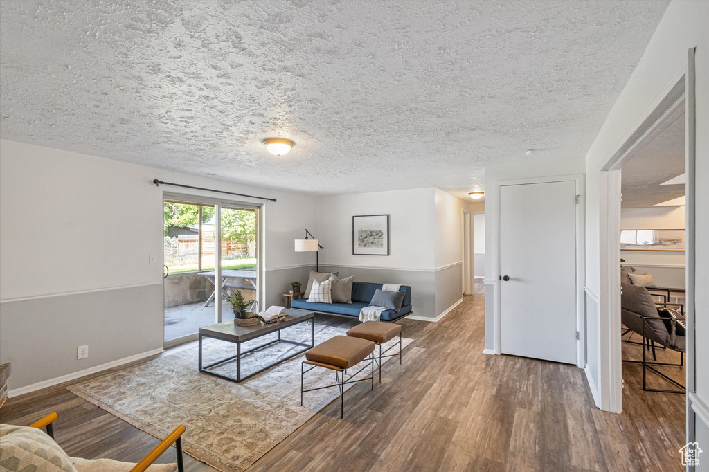 Living area with wood finished floors, baseboards, and a textured ceiling