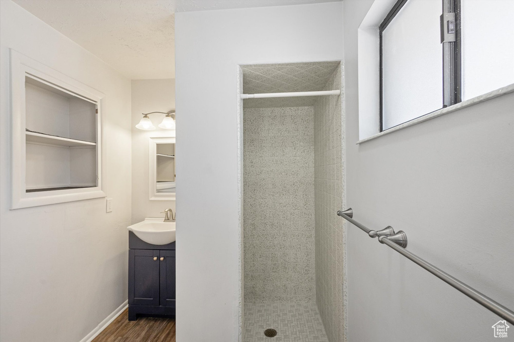 Bathroom featuring vanity, a stall shower, wood finished floors, and baseboards