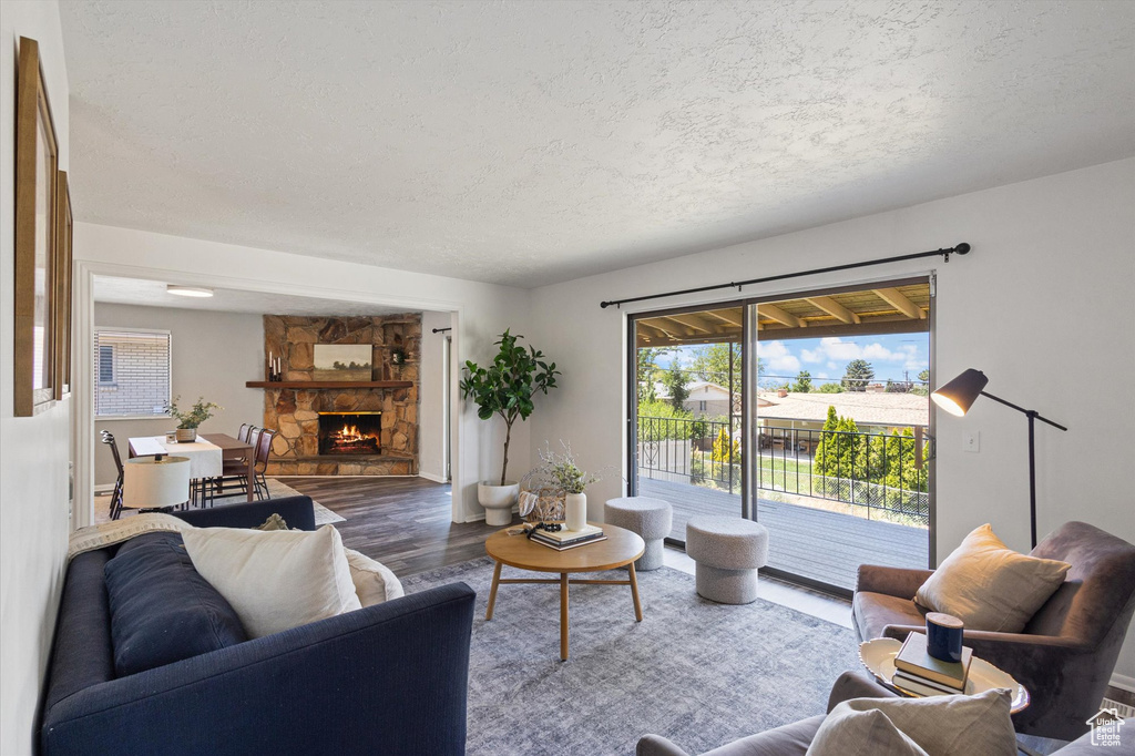 Living area with a textured ceiling, wood finished floors, and a stone fireplace
