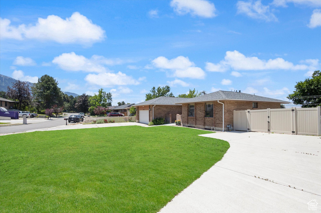 Ranch-style home with a gate, driveway, an attached garage, and brick siding