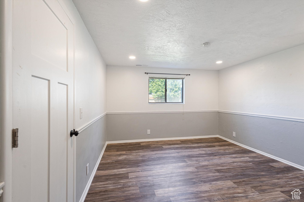 Empty room with wood finished floors, recessed lighting, a textured ceiling, and baseboards