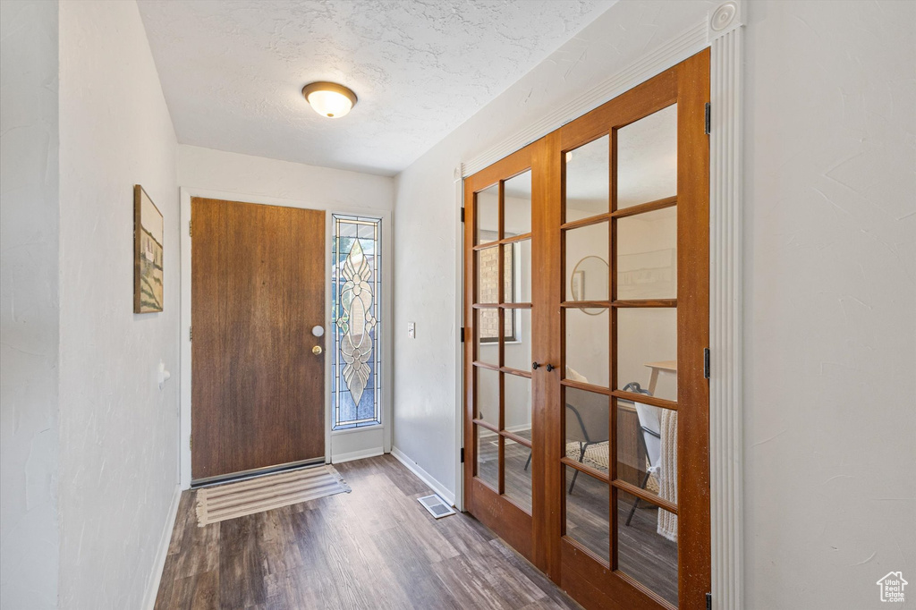 Entryway featuring french doors, wood finished floors, baseboards, and a textured ceiling