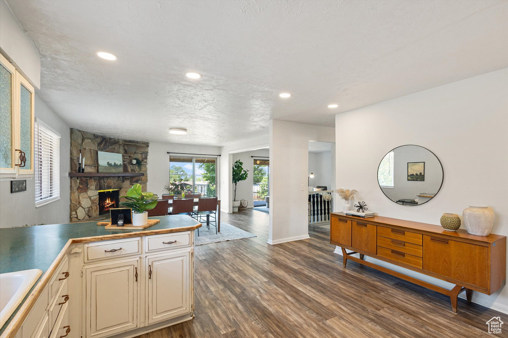 Kitchen featuring dark wood-type flooring, a fireplace, recessed lighting, cream cabinetry, and a sink