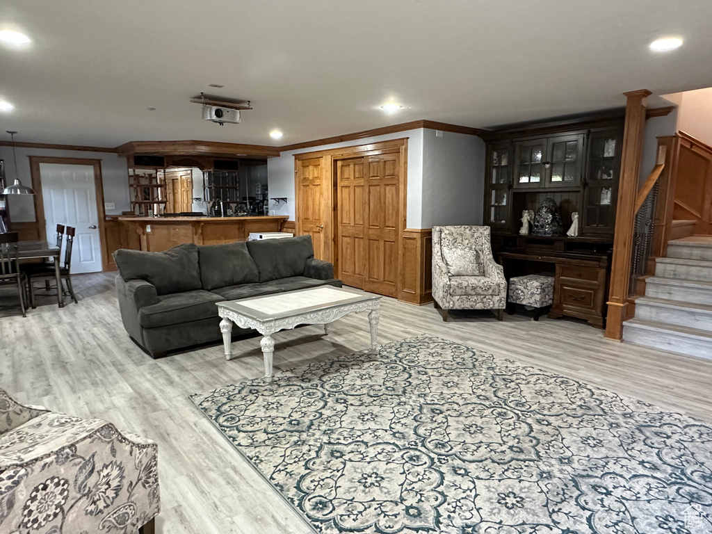 Living area with wood finished floors, stairs, and ornamental molding