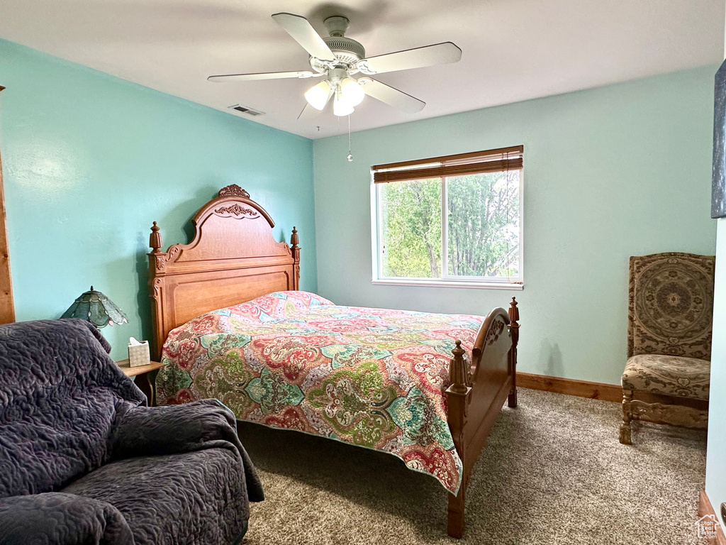 Carpeted bedroom featuring a ceiling fan and baseboards