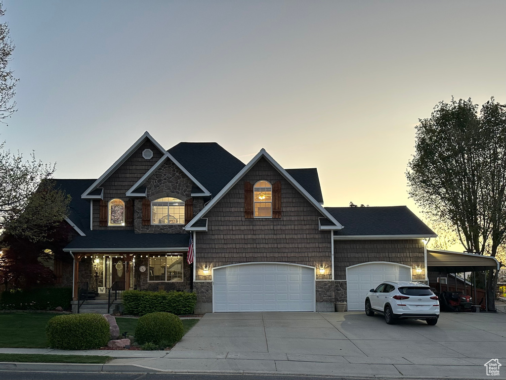 Craftsman house featuring stone siding, driveway, a garage, and a porch