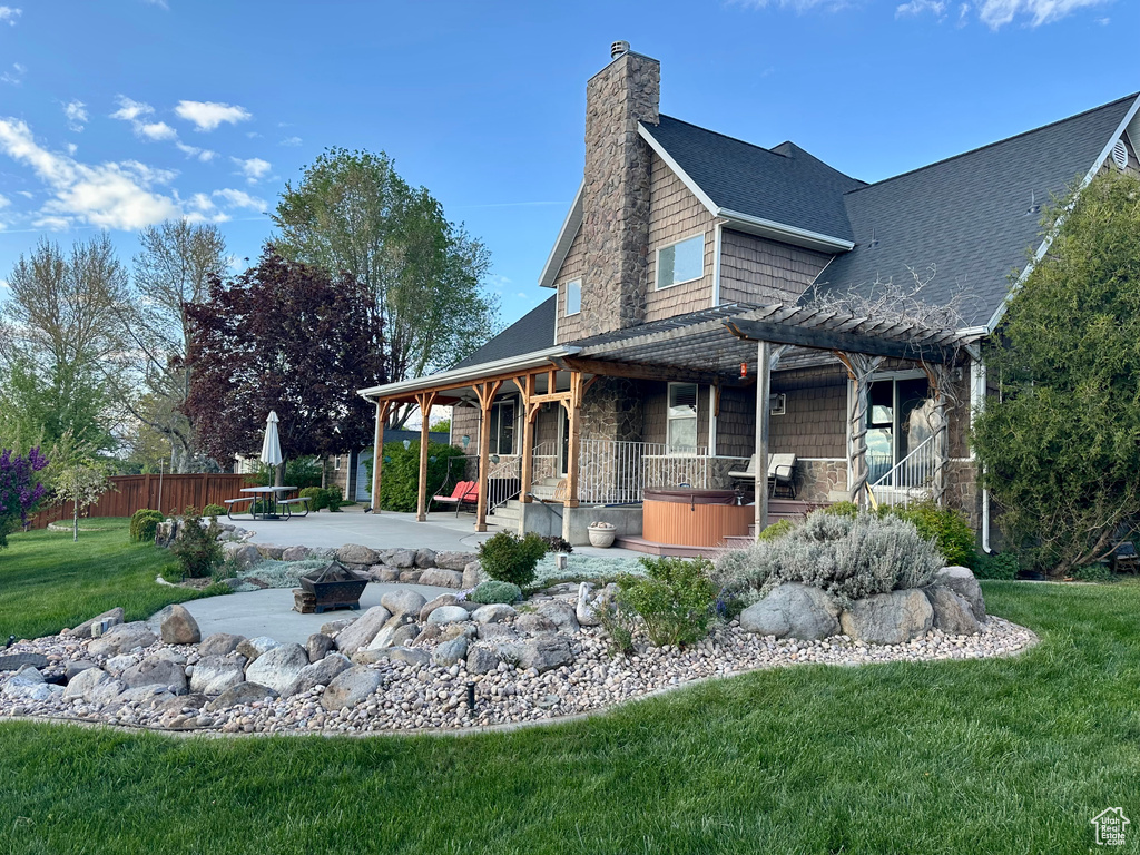 Rear view of house with an outdoor fire pit, a patio area, a chimney, a shingled roof, and stone siding