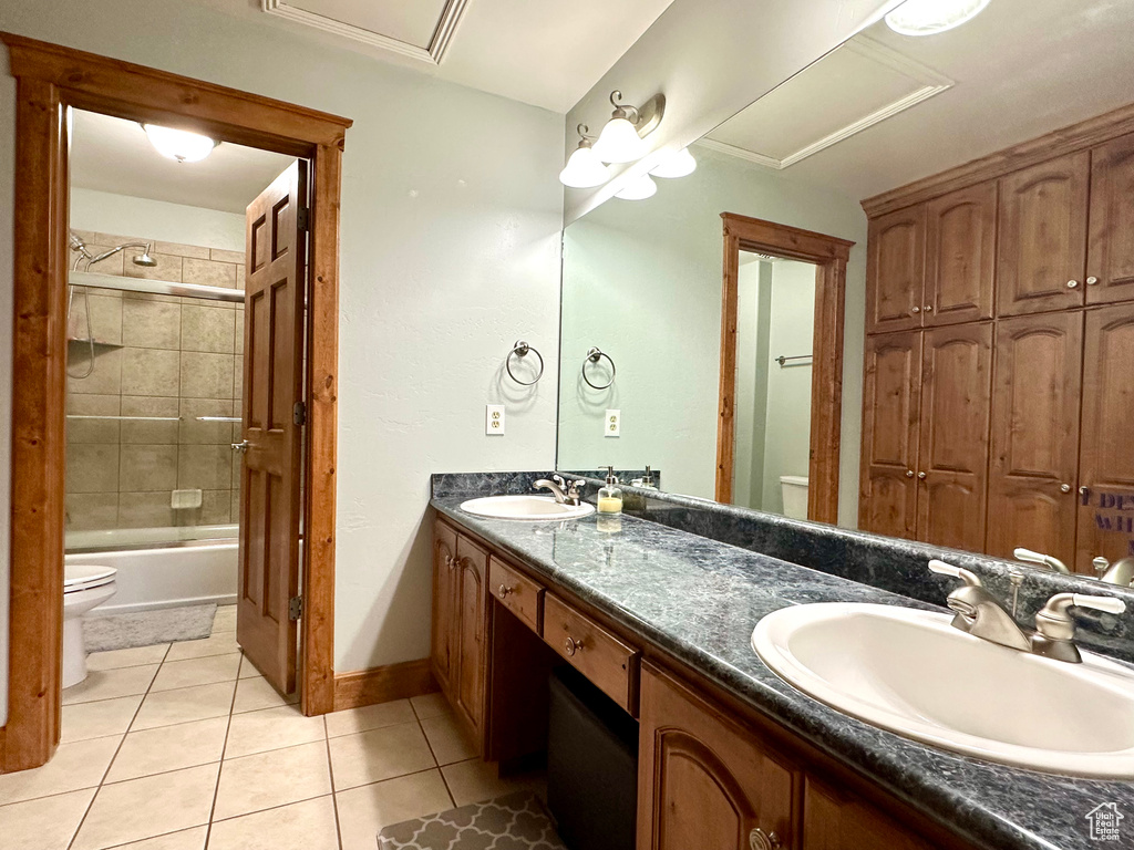 Bathroom featuring toilet, tile patterned floors, double vanity, and baseboards