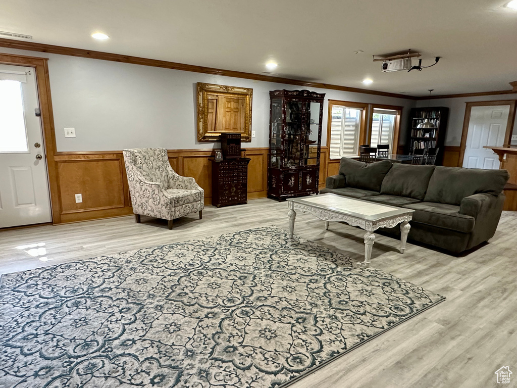 Living area featuring light wood-type flooring, ornamental molding, a wainscoted wall, and recessed lighting