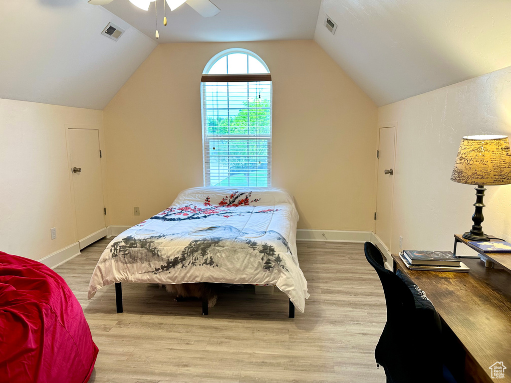 Bedroom with light wood-style flooring, lofted ceiling, baseboards, and ceiling fan