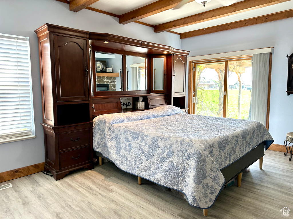 Bedroom featuring beam ceiling, light wood-type flooring, access to exterior, multiple windows, and baseboards