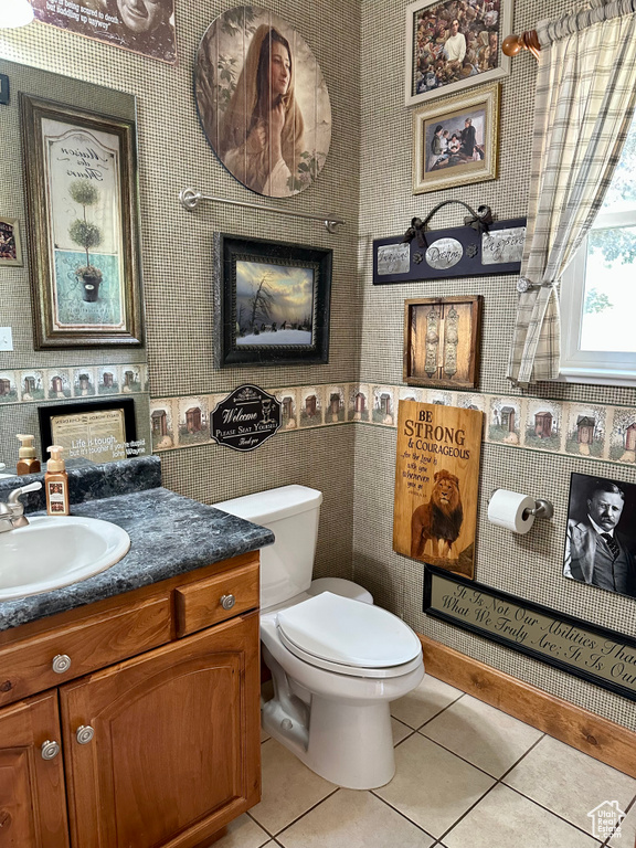 Bathroom with vanity, tile patterned floors, toilet, and wallpapered walls