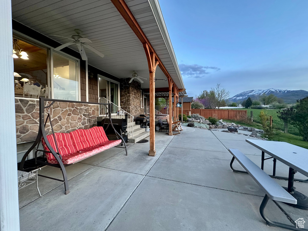 Fenced backyard with ceiling fan, a mountain view, and a patio area