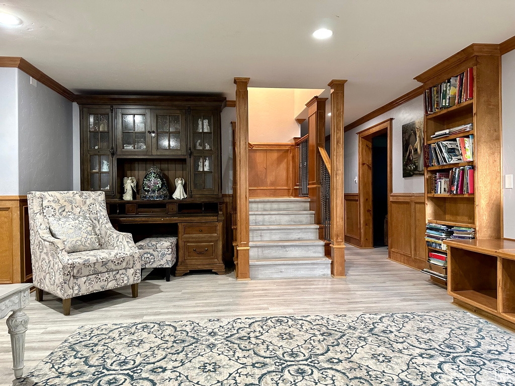 Sitting room with crown molding, a wainscoted wall, light wood-type flooring, and stairway