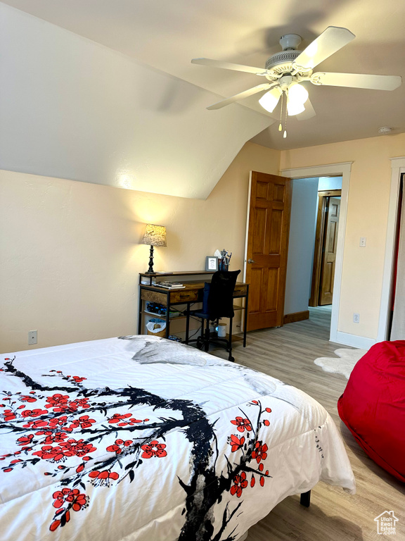 Bedroom with wood finished floors, vaulted ceiling, ceiling fan, and baseboards